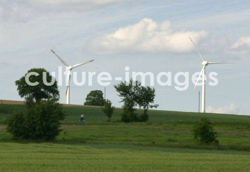 Radfahrer vor Windrädern in Feldern Radfahrer vor Windrädern in Feldern